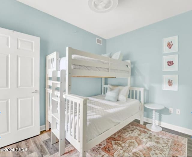 bedroom featuring visible vents, baseboards, and wood finished floors