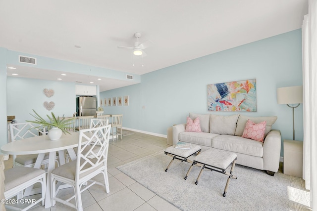 living area with light tile patterned floors, baseboards, visible vents, and a ceiling fan