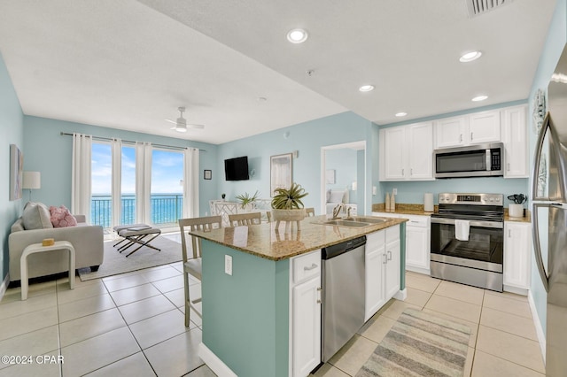 kitchen with white cabinets, an island with sink, appliances with stainless steel finishes, open floor plan, and a sink