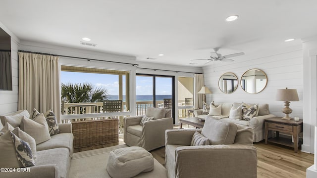 living room with a water view, ceiling fan, and light wood-type flooring