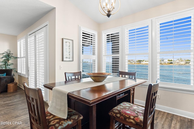 dining area featuring a water view, lofted ceiling, dark hardwood / wood-style floors, and a chandelier