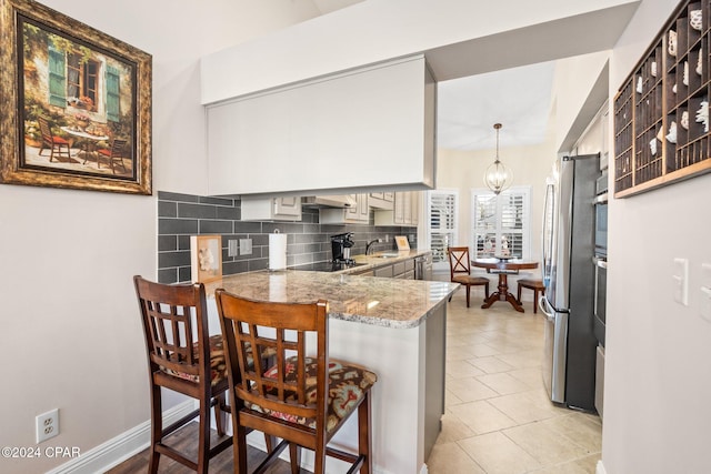 kitchen featuring a kitchen bar, sink, hanging light fixtures, kitchen peninsula, and decorative backsplash