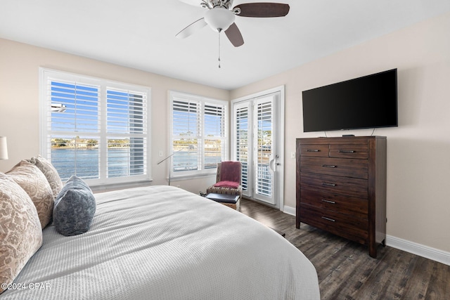 bedroom with dark hardwood / wood-style flooring, access to outside, ceiling fan, and a water view