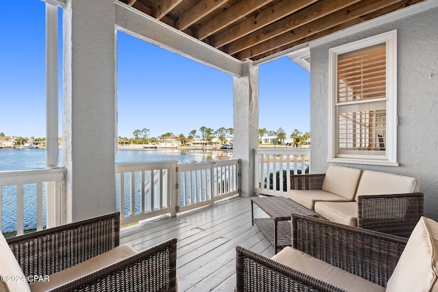 wooden terrace with a water view and an outdoor hangout area