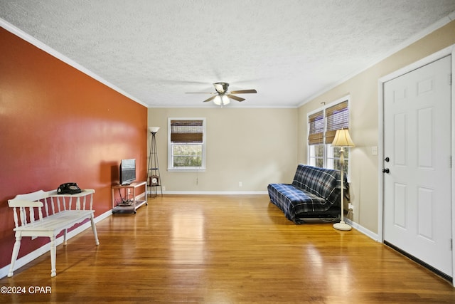 sitting room featuring ceiling fan, ornamental molding, a textured ceiling, and wood-type flooring