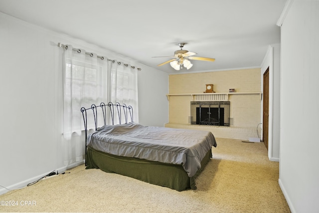 carpeted bedroom featuring ceiling fan, a brick fireplace, and ornamental molding