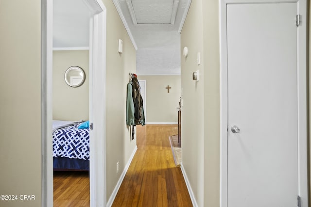 hallway featuring crown molding, hardwood / wood-style floors, and a textured ceiling