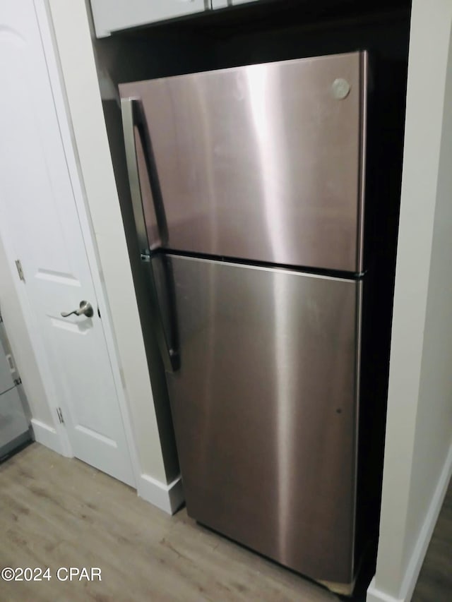 interior details featuring stainless steel fridge and light hardwood / wood-style floors