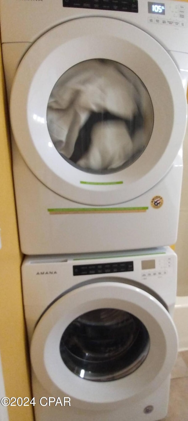 laundry room with tile patterned floors and stacked washing maching and dryer