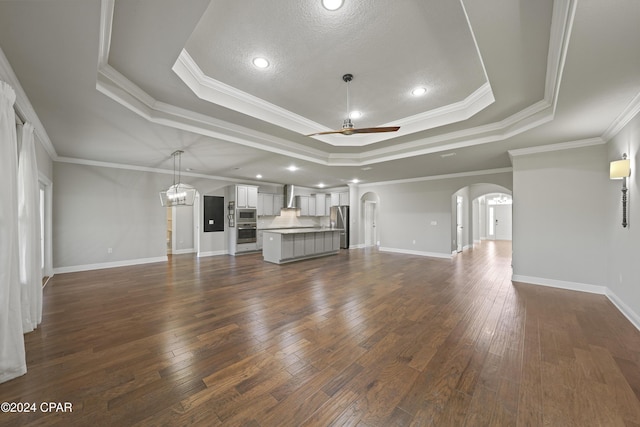 unfurnished living room featuring ceiling fan, ornamental molding, and a tray ceiling