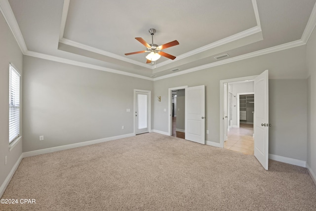 unfurnished bedroom with a tray ceiling, ceiling fan, and ornamental molding