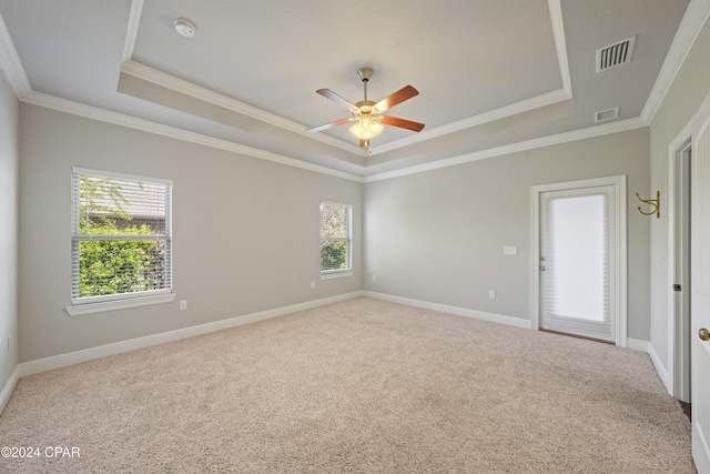 carpeted empty room featuring ceiling fan, a raised ceiling, and ornamental molding