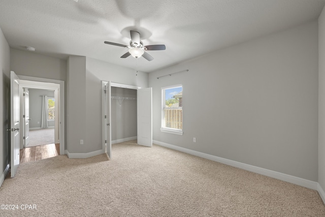 unfurnished bedroom featuring ceiling fan, a closet, carpet floors, and a textured ceiling