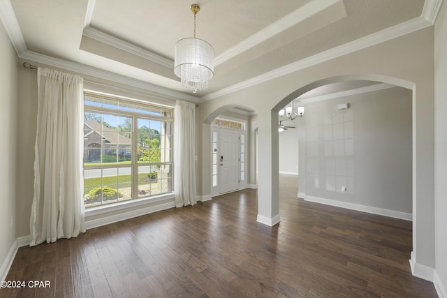 spare room with a chandelier, dark hardwood / wood-style flooring, a tray ceiling, and crown molding