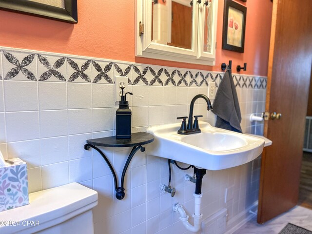 bathroom featuring sink, tile walls, and toilet