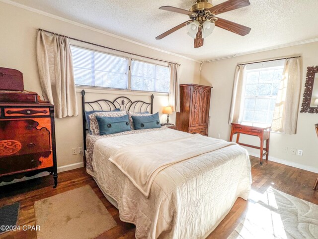 bedroom featuring hardwood / wood-style flooring, ceiling fan, multiple windows, and a textured ceiling