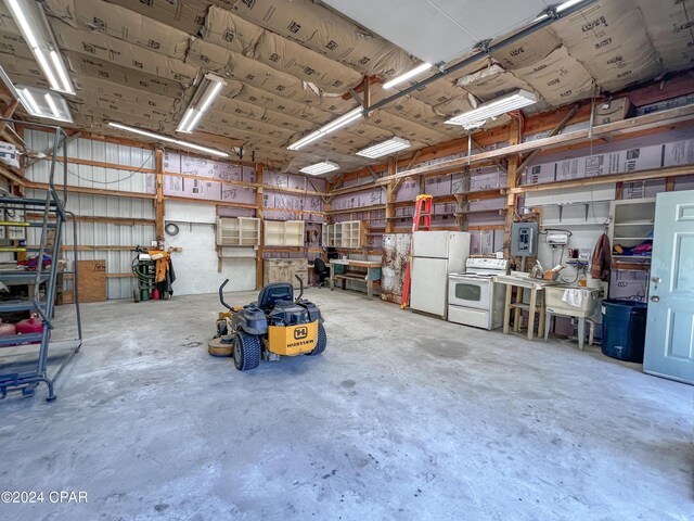 garage featuring white refrigerator, electric panel, and a workshop area