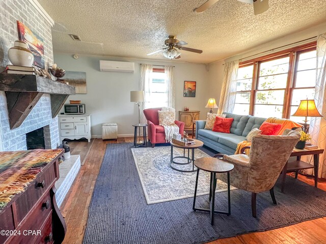 living room with ceiling fan, a wall unit AC, a textured ceiling, dark hardwood / wood-style flooring, and a brick fireplace