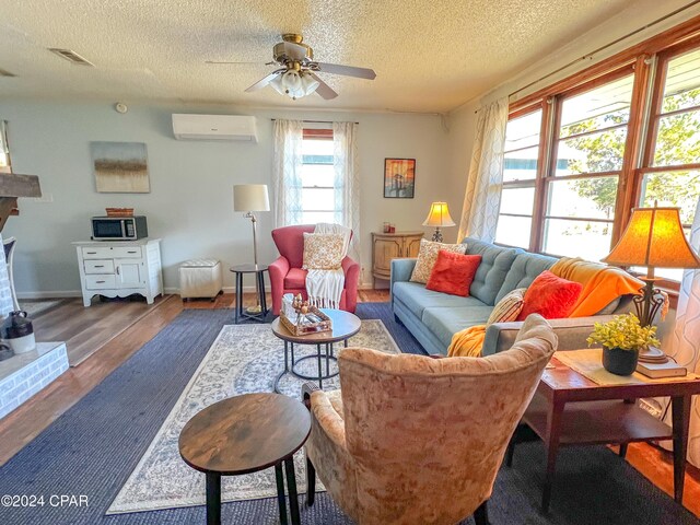 living room featuring a fireplace, a wall mounted AC, dark hardwood / wood-style flooring, ceiling fan, and a textured ceiling