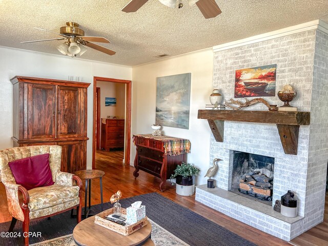 living room with ceiling fan, a fireplace, hardwood / wood-style floors, and a textured ceiling