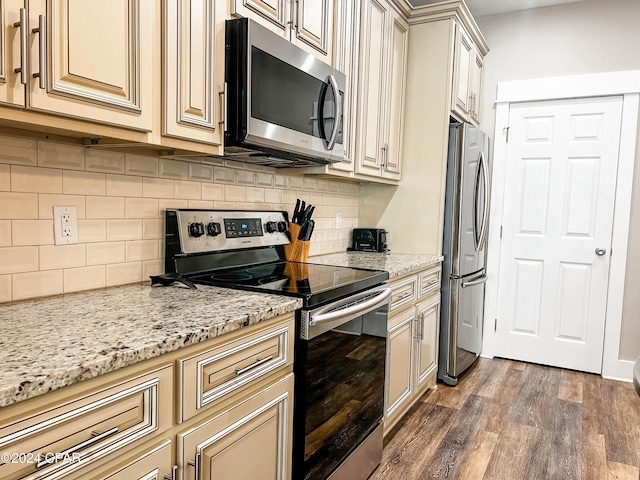 101 S 39th St Unit C, Mexico Beach, FL 32456 - kitchen with appliances with stainless steel finishes, cream cabinets, wood finished floors, light stone counters, and decorative backsplash