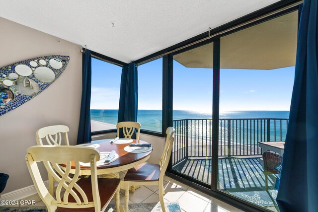 dining room with a textured ceiling, a water view, and light tile patterned floors