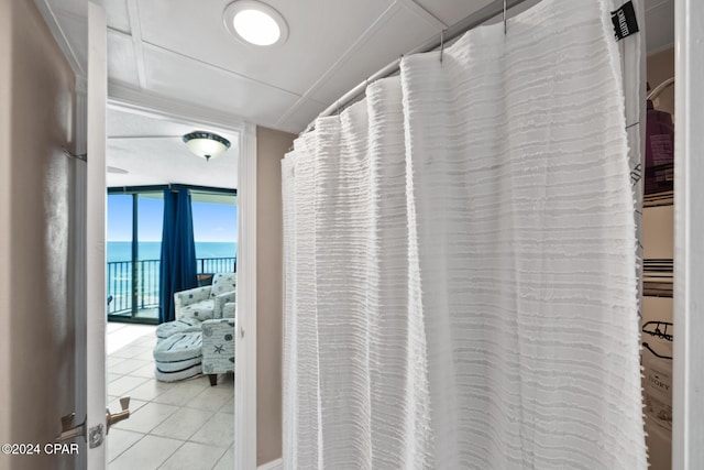 bathroom featuring a water view, floor to ceiling windows, and tile patterned flooring