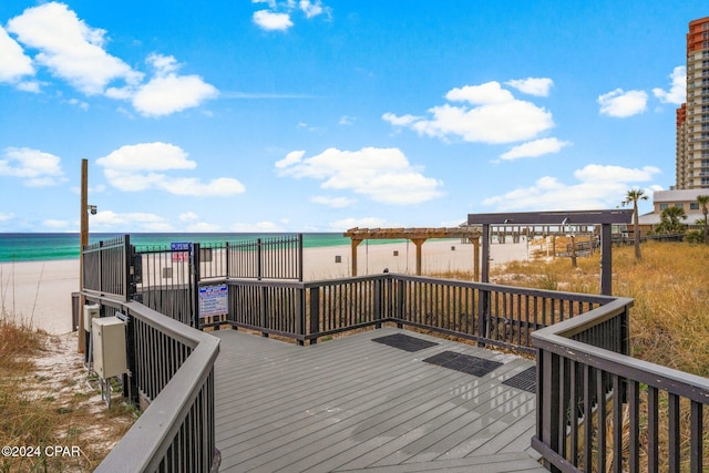 wooden terrace featuring a water view and a view of the beach