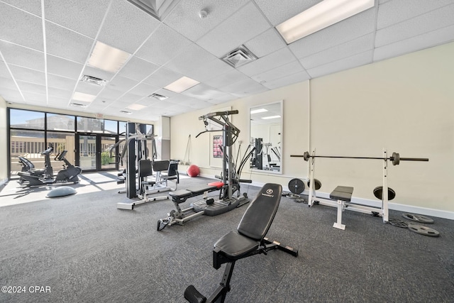 workout area featuring a wall of windows and a paneled ceiling