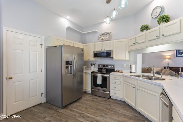 kitchen featuring appliances with stainless steel finishes, sink, a towering ceiling, dark hardwood / wood-style flooring, and hanging light fixtures