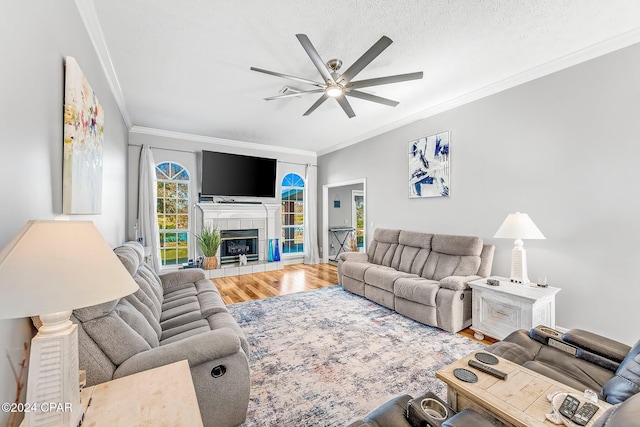 living room with a fireplace, wood-type flooring, ornamental molding, and a textured ceiling