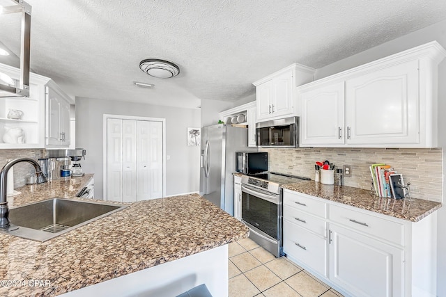 kitchen featuring light tile patterned flooring, white cabinetry, sink, backsplash, and stainless steel appliances