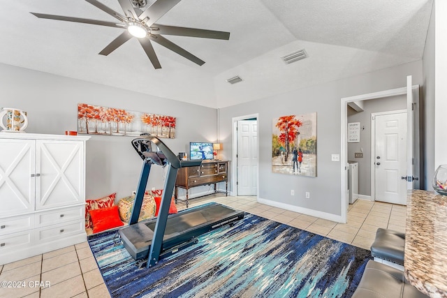 exercise room featuring ceiling fan, tile patterned flooring, and vaulted ceiling