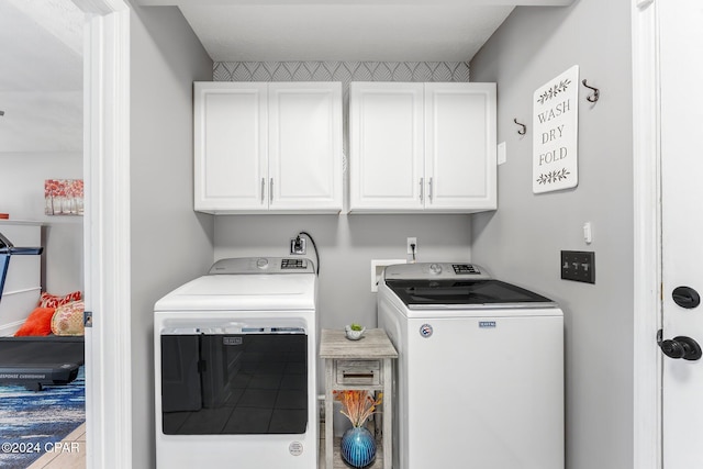 clothes washing area with washer and dryer and cabinets