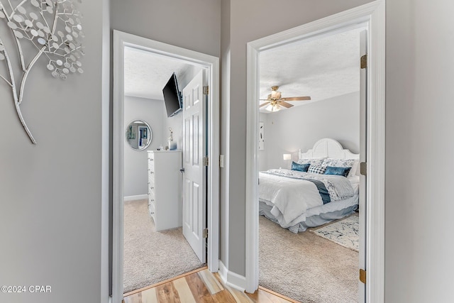 bedroom featuring ceiling fan, light colored carpet, and a textured ceiling