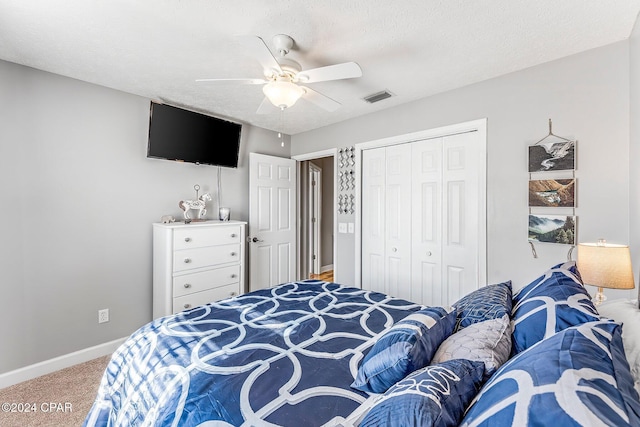 carpeted bedroom with ceiling fan, a closet, and a textured ceiling