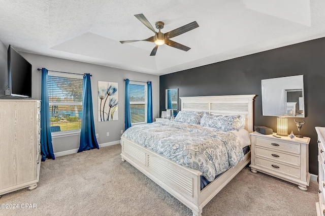 carpeted bedroom with ceiling fan, a raised ceiling, and a textured ceiling