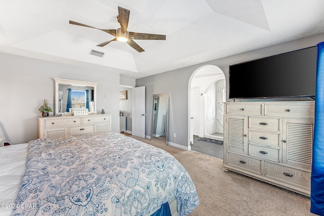 carpeted bedroom featuring ceiling fan and a tray ceiling