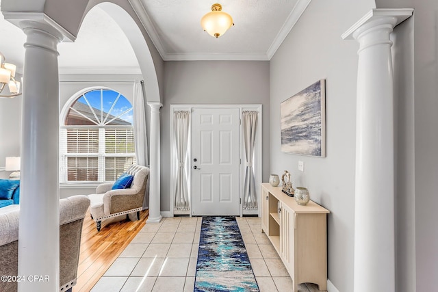 entrance foyer with ornate columns, ornamental molding, and light tile patterned floors