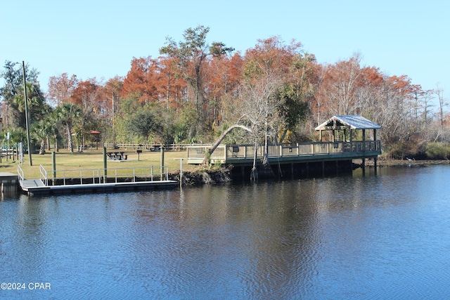 view of dock featuring a lawn and a water view