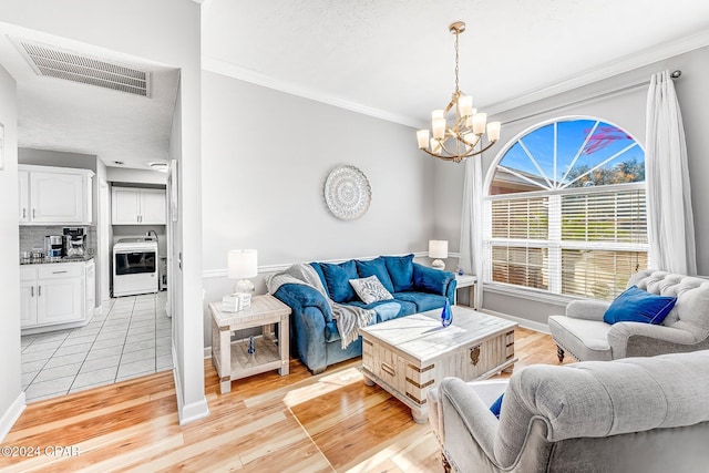 living room with washer / clothes dryer, a chandelier, ornamental molding, a textured ceiling, and light hardwood / wood-style flooring