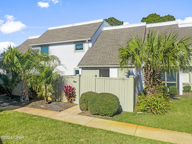 view of front of property featuring roof with shingles, fence, and a front yard