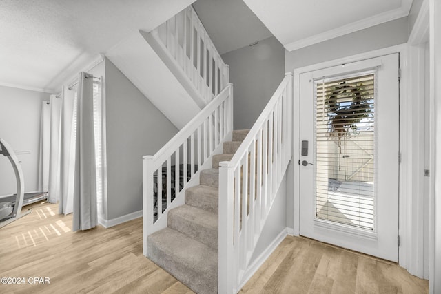 staircase featuring baseboards, wood finished floors, a wealth of natural light, and crown molding