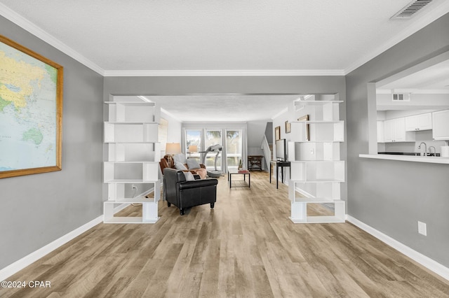 interior space with ornamental molding, light wood-type flooring, visible vents, and baseboards