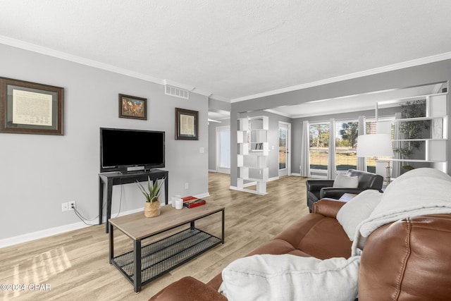 living room with light wood-style flooring, a textured ceiling, visible vents, and crown molding