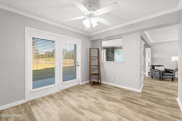 empty room with ceiling fan, a textured ceiling, baseboards, ornamental molding, and light wood-type flooring