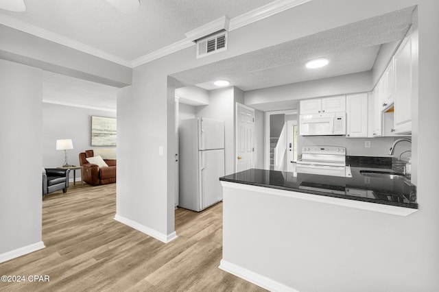 kitchen featuring dark countertops, visible vents, white cabinets, a sink, and white appliances