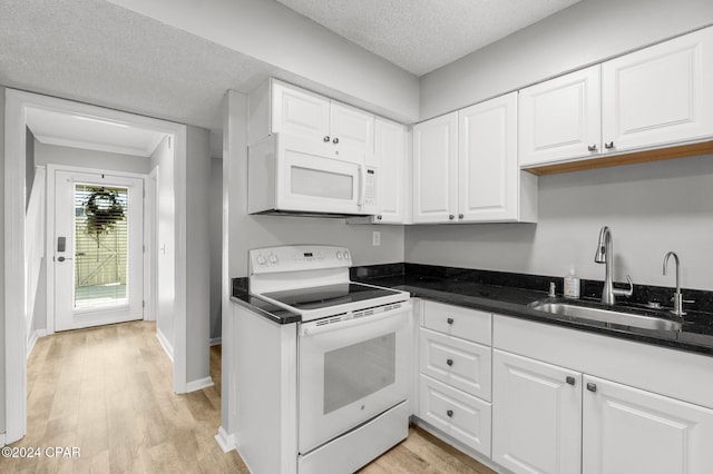 kitchen with white appliances, white cabinets, dark countertops, a textured ceiling, and a sink