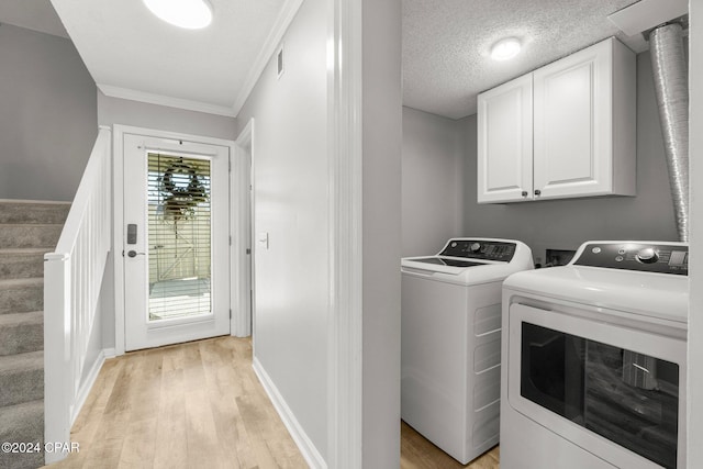 laundry room with light wood finished floors, cabinet space, a textured ceiling, independent washer and dryer, and baseboards