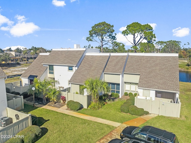 view of front of property with a front lawn, roof with shingles, and fence